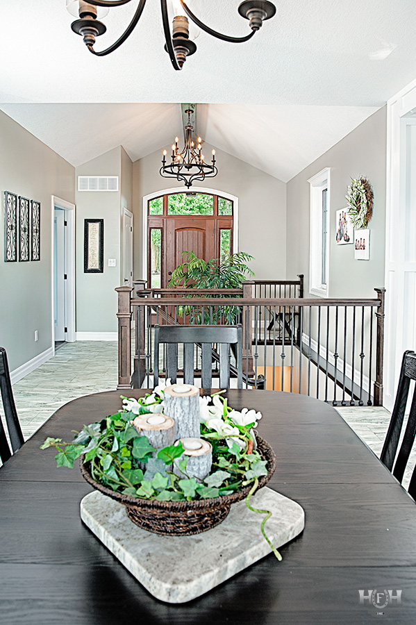 kitchen dining table with flower arrangement and stairs to basement and front door in background