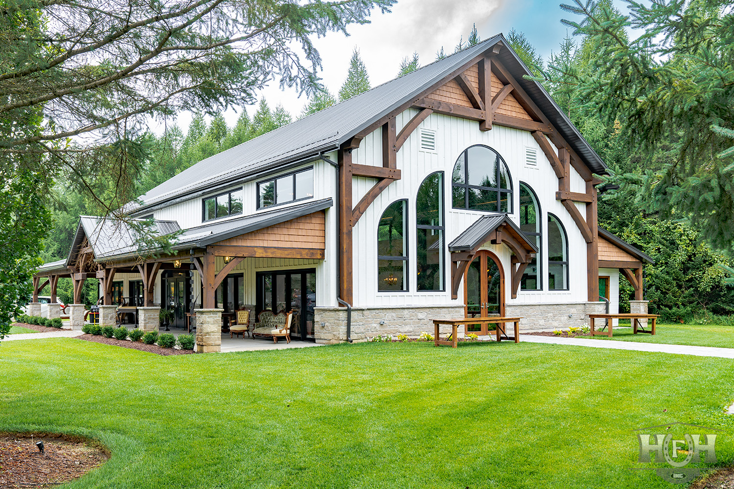 Exterior side angle of white wedding venue framed by pine trees