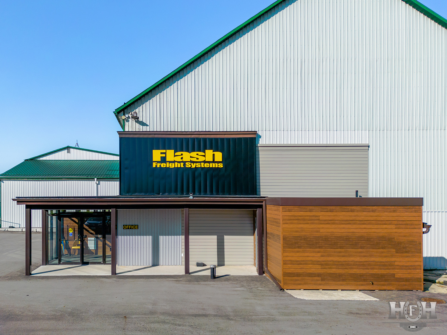 Exterior commercial building with grey siding and yellow company name